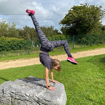 Young girl practicing yoga on rock